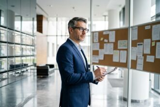 Syndic de copropriété examinant des documents dans le hall d'entrée d'un grand immeuble résidentiel moderne