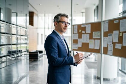 Syndic de copropriété examinant des documents dans le hall d'entrée d'un grand immeuble résidentiel moderne